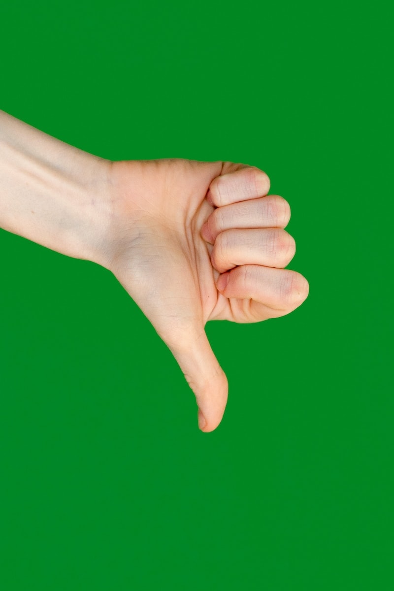 a person's hand holding a cell phone in front of a green background